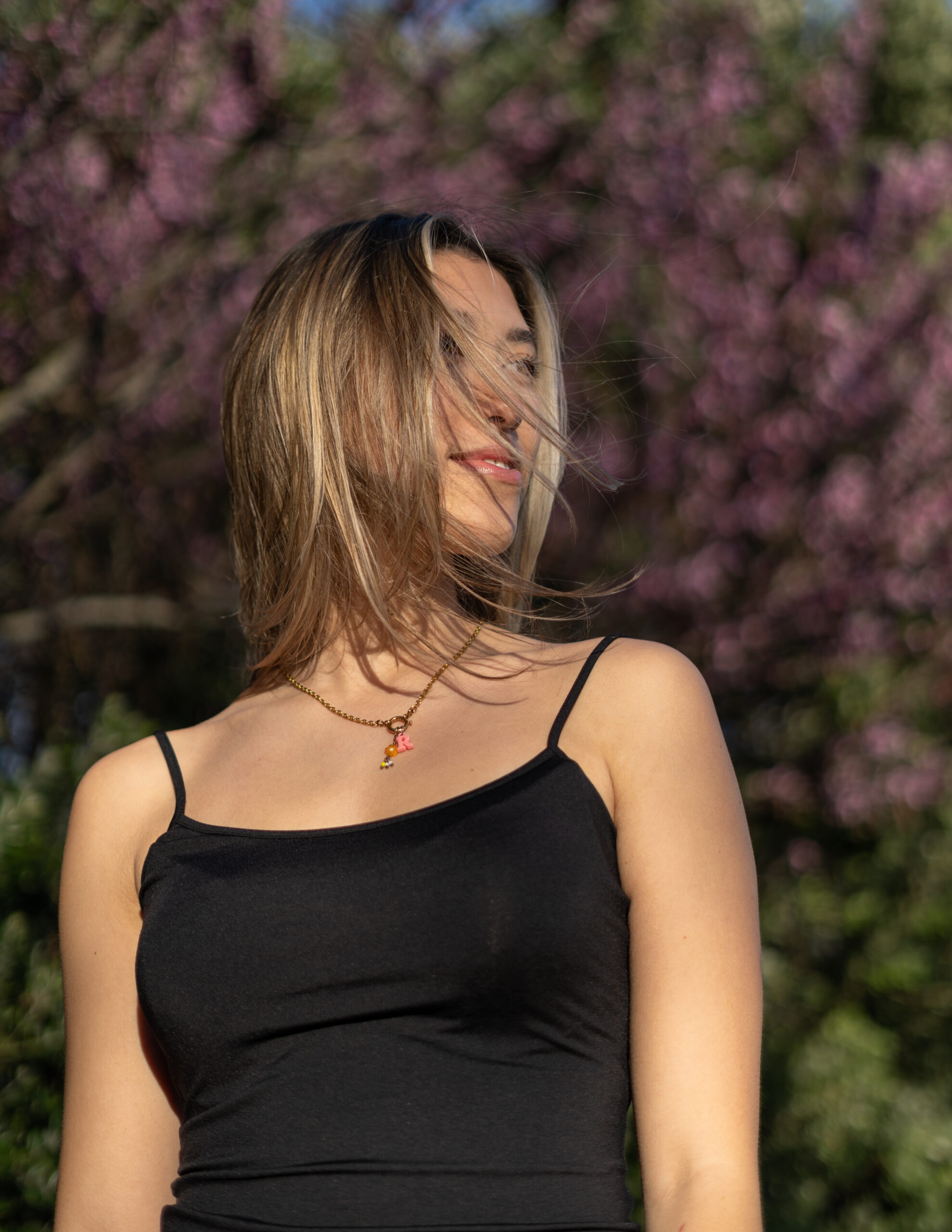 Girl with hair flowing in front of a pink blossom