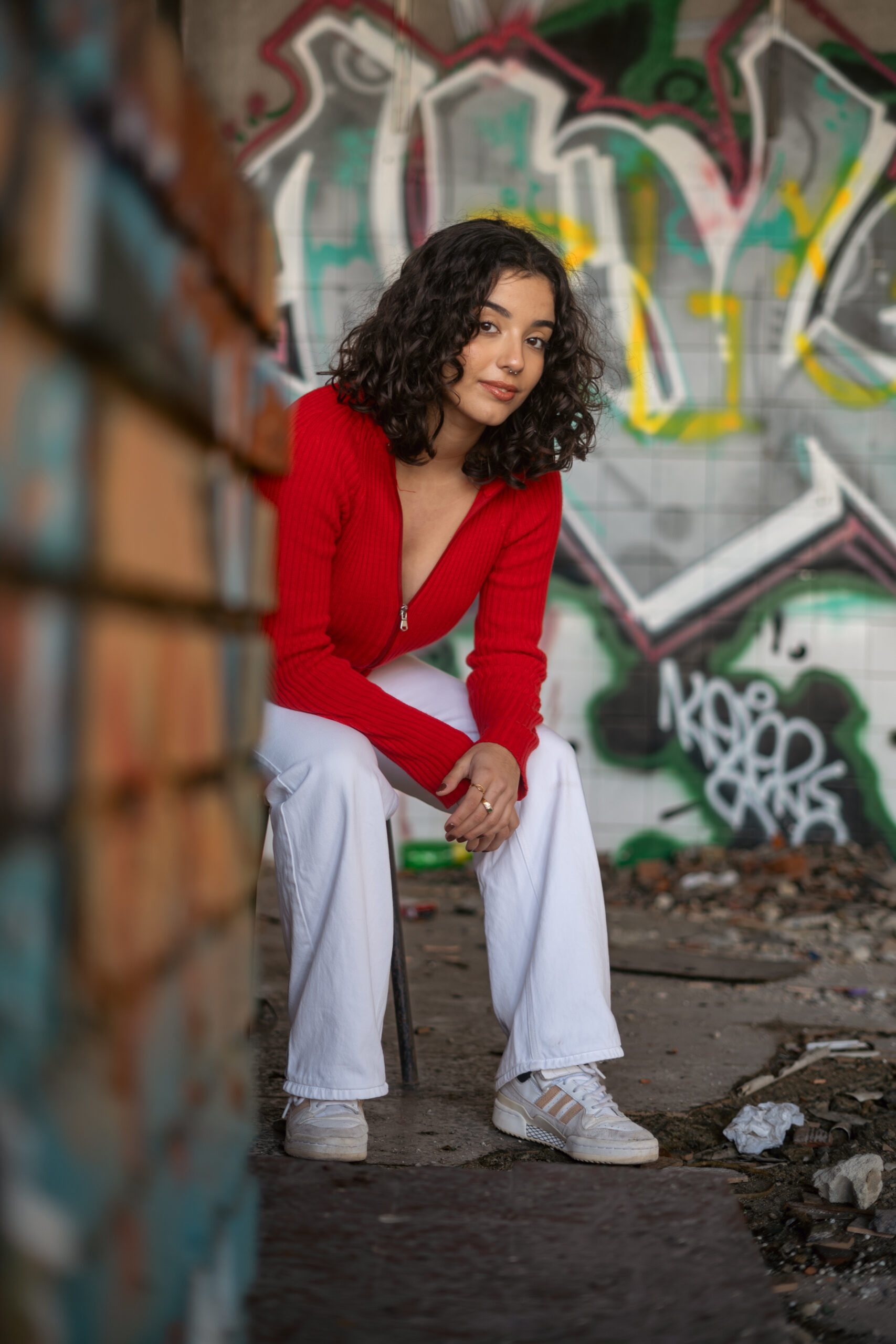 Girl in streety outfit sitting on a chair in an abondoned building