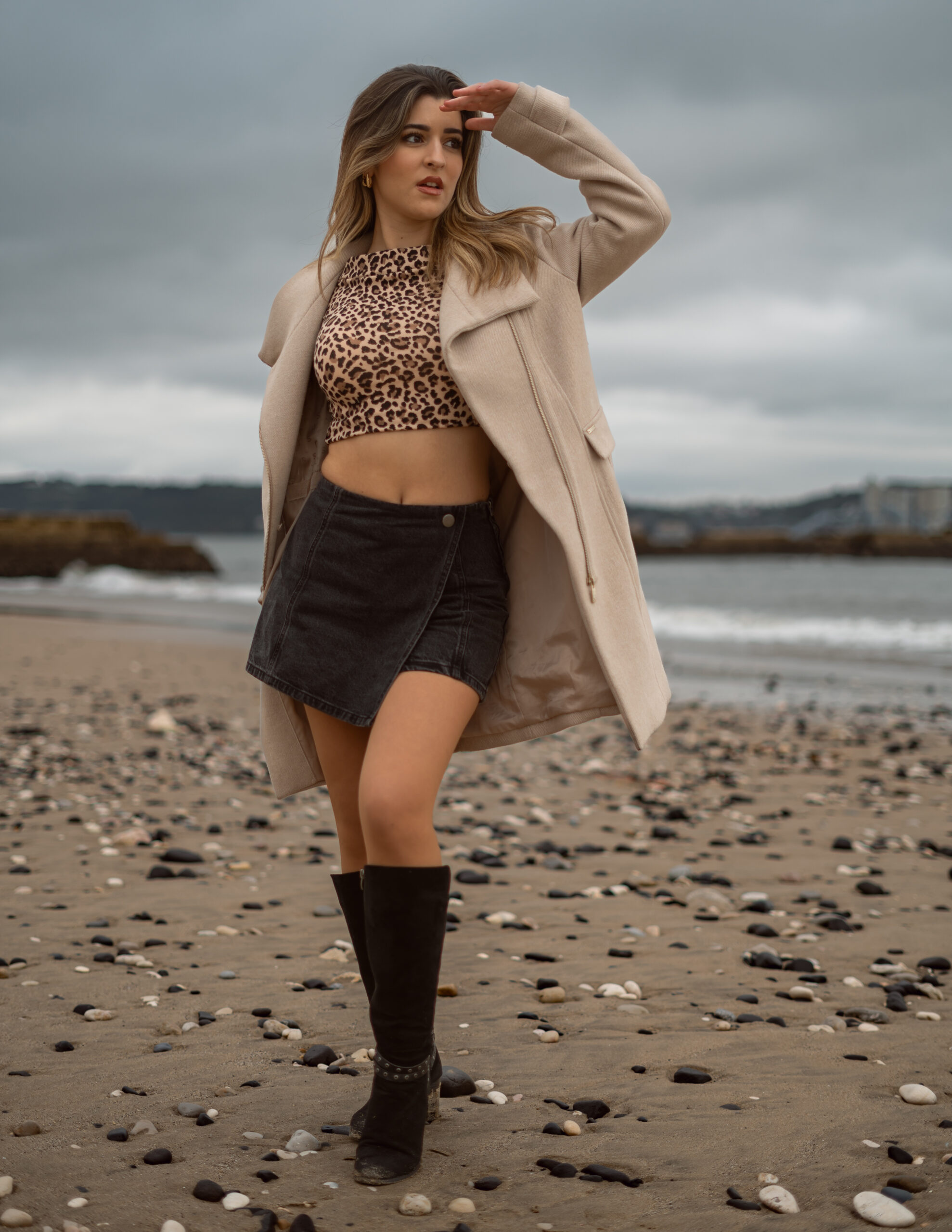 Girl at the beach in winter outfit with pebbles around
