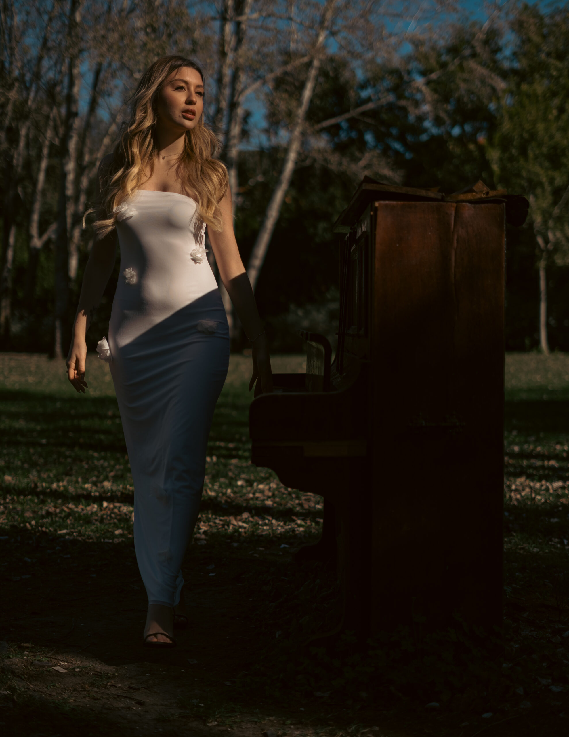Girl in white dress touching antique piano