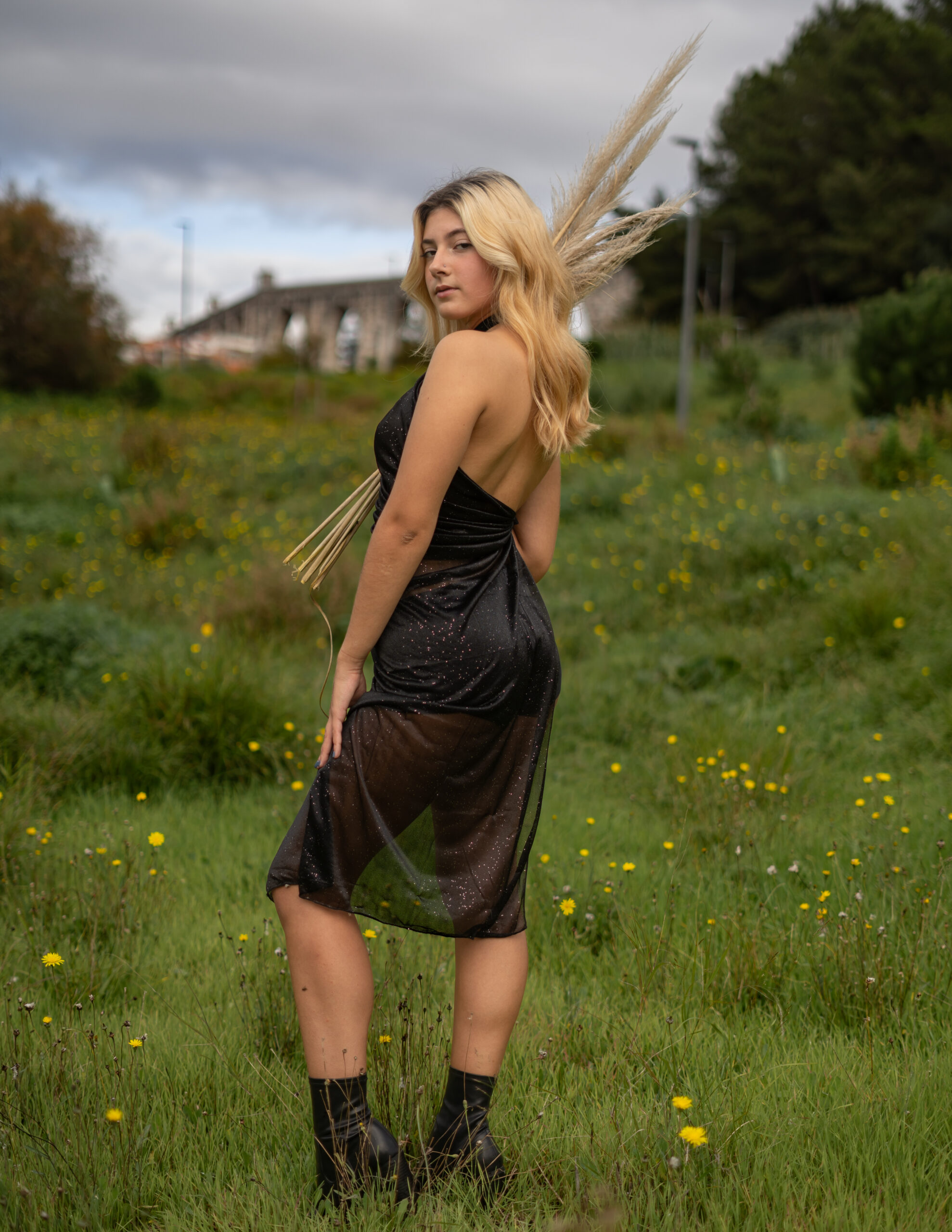 Girl in an open field surrounded by flowers holding tall grass