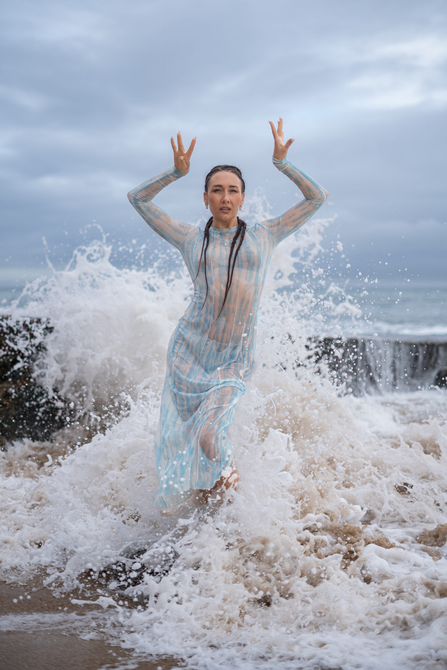 Girl dancing as the wave crashes behind her